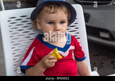 Das Porträt einer schönen jungen mit einem blauen Hut genießen Sie ein leckeres Eis. Er ist ein gelbes Eis in der Hand. Stockfoto