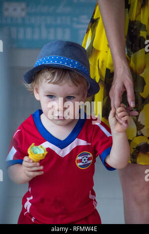 Aa portrait einer jungen Costa Rica Football team Fan, ein Spiel, das mit seiner Mutter. Der Junge ist ein pistazieneis. Stockfoto