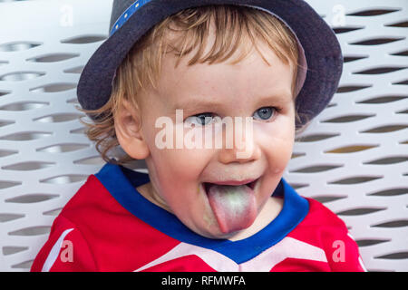 Das Porträt einer jungen, die Zunge nach einem köstlichen Pistazieneis Stockfoto