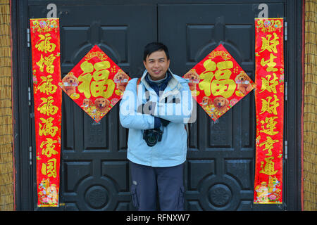 Harbin, China - Feb 23, 2018. Ein junger Mann stand vor der ländlichen Haus mit Dekorationen für Neujahr. Stockfoto