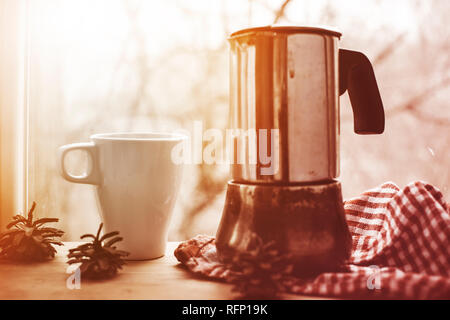 Eine Tasse Kaffee auf dem Hintergrund der Geysir Kaffeemaschine und Fenster mit Regentropfen. Closeup, selektiver Fokus, Holz- Oberfläche Stockfoto