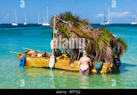 Frau, die einen Kauf von einer schwimmenden Obst shop Shanty boot Reduit Beach, Rodney Bay, St. Lucia, Karibik. Stockfoto