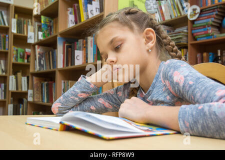 Ein Mädchen von zehn Jahre alt ist, ein Buch zu lesen im Lesesaal Stockfoto