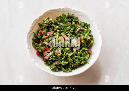 Gehackte Petersilie Salat mit Tomaten und Zwiebeln in Keramik Schüssel auf Marmor Oberfläche. Ökologische Lebensmittel. Stockfoto