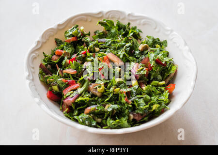 Gehackte Petersilie Salat mit Tomaten und Zwiebeln in Keramik Schüssel auf Marmor Oberfläche. Ökologische Lebensmittel. Stockfoto