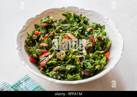 Gehackte Petersilie Salat mit Tomaten und Zwiebeln in Keramik Schüssel auf Marmor Oberfläche. Ökologische Lebensmittel. Stockfoto