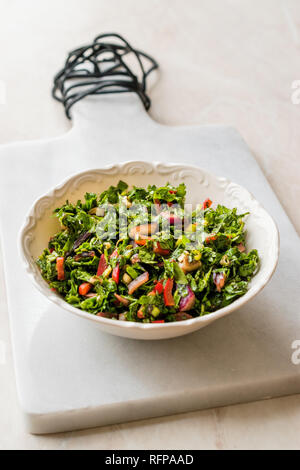 Gehackte Petersilie Salat mit Tomaten und Zwiebeln in Keramik Schüssel auf Marmor. Ökologische Lebensmittel. Stockfoto