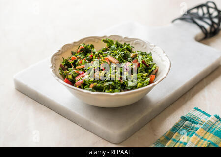Gehackte Petersilie Salat mit Tomaten und Zwiebeln in Keramik Schüssel auf Marmor. Ökologische Lebensmittel. Stockfoto