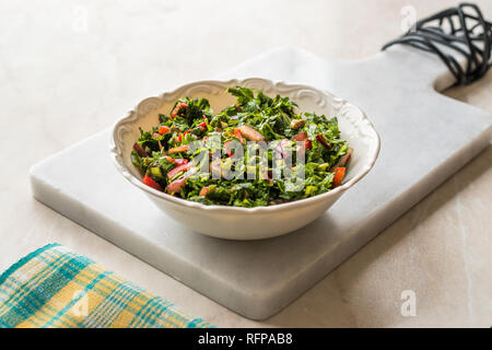 Gehackte Petersilie Salat mit Tomaten und Zwiebeln in Keramik Schüssel auf Marmor. Ökologische Lebensmittel. Stockfoto