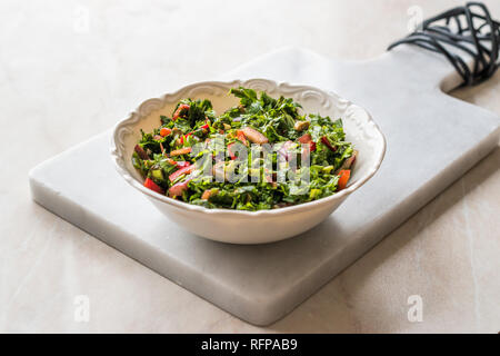 Gehackte Petersilie Salat mit Tomaten und Zwiebeln in Keramik Schüssel auf Marmor. Ökologische Lebensmittel. Stockfoto