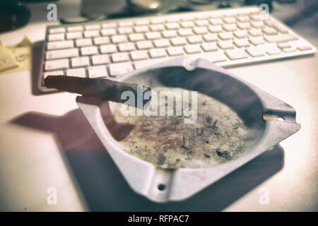 Toscano Zigarren Brennen auf einen Aschenbecher. Computer Tastatur im Hintergrund. Stockfoto