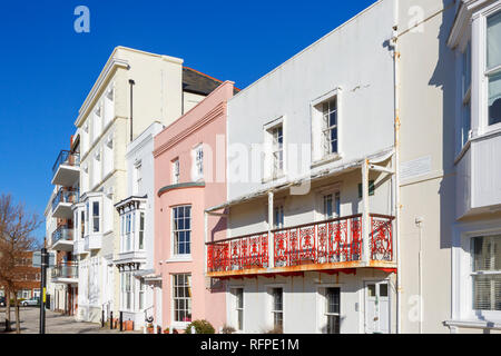 Georgische Häuser in Grand Parade, Portsmouth, Hampshire, Großbritannien, darunter auch Reihenhäuser mit rosa Schleife mit Glasfassade, Fenster und roten schmiedeeisernen Balkon Stockfoto