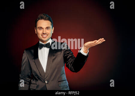 Berufliche Tätigkeit. Showman in der Klage stehen isoliert auf Wand, Kopie Raum suchen Kamera freundlich Stockfoto