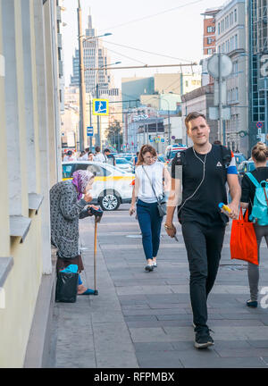 Moskau, Russland - September 6, 2018: Ältere Frau bittet um Almosen von Passanten auf der Straße. Rentner ständigen beugte sich mit einem Stock Kreuz selbst und Stockfoto