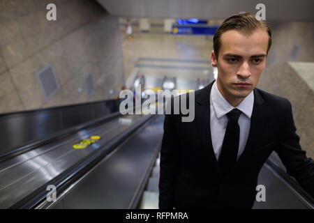 Junge Unternehmer stehen in Rolltreppe im Bahnhof Stockfoto