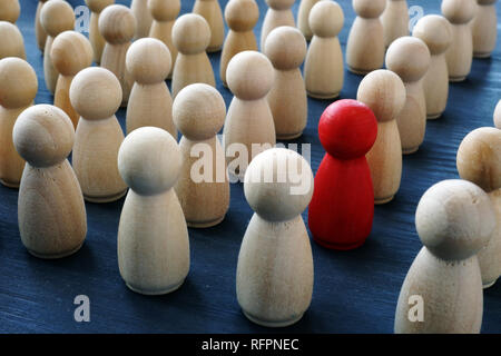 Einzigartigkeit, Individualität und Differenz. Rote hölzerne Figur in einer Menschenmenge. Stockfoto