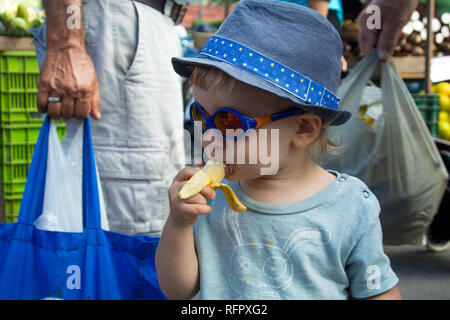 Ein Junge, der ein köstliches Dessert Banane, ein guter Ersatz für Bonbons und andere Süßigkeiten. Santa Ana, Costa Rica Stockfoto