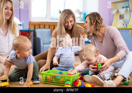Gruppe von Mütter und ihre Babys spielen in Day care center Stockfoto
