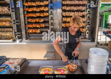 Frau bereitet Speisen zum Mitnehmen vor der Hühner wird am Spieß gebraten auf der Seite eines van im spanischen Markt Stockfoto