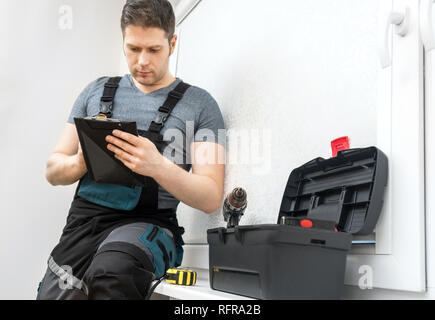 Professionelle Auftragnehmer auf Fenster mit Stift und Notizblock sitzen. Stockfoto