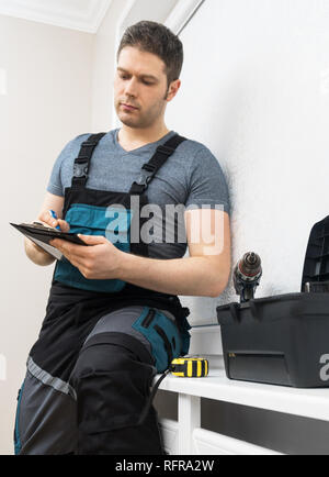 Professionelle Auftragnehmer auf Fenster mit Stift und Notizblock sitzen. Stockfoto