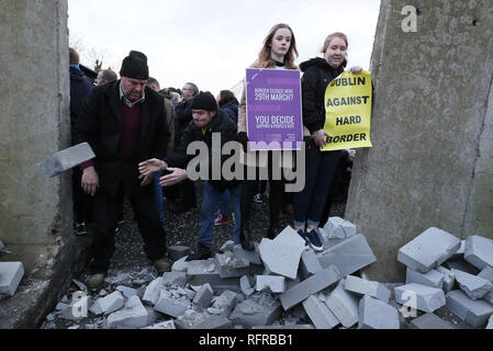 Die Demonstranten knock down eine symbolische Mauer, die als Teil einer anti-Brexit Kundgebung an der irischen Grenze in der Nähe von Carrickcarnan, Co Louth gebaut wurde. Stockfoto