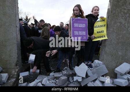 Die Demonstranten knock down eine symbolische Mauer, die als Teil einer anti-Brexit Kundgebung an der irischen Grenze in der Nähe von Carrickcarnan, Co Louth gebaut wurde. Stockfoto