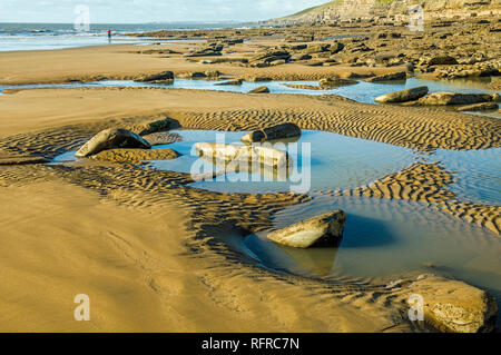 Dunraven Bay Southerndown Glamorgan Heritage Coast South Wales mit einer Person in der Ferne und Sand und Pools im Vordergrund. Stockfoto