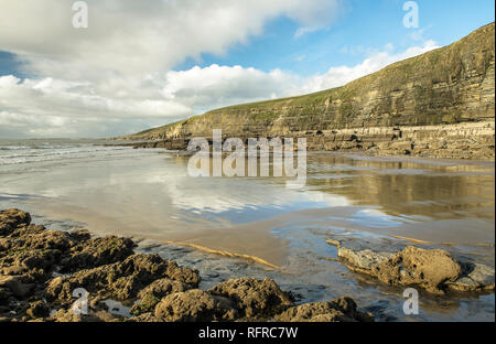 Dunraven Bay, Southerndown an der Glamorgan Heritage Coast. Der Winter Sonne verursacht cloud Reflexionen in den nassen Sand Stockfoto