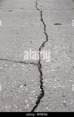 Risse in der Betondecke der Straße in Form einer gestrichelten Linie. Stockfoto