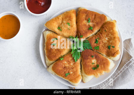 Frittierte Fleischpasteten mit Soßen, samsa, Samosas, echpochmak - traditionelle Fleisch oder vegetarisch gefüllte Pasteten Pasteten auf weißem Hintergrund, kopieren. Stockfoto