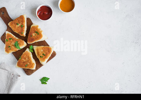 Frittierte Fleischpasteten mit Soßen, samsa, Samosas, echpochmak - traditionelle Fleisch oder vegetarisch gefüllte Pasteten Pasteten auf weißem Hintergrund, kopieren. Stockfoto