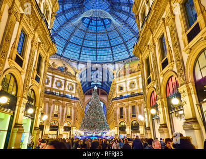 Menschen zu Fuß auf die Galleria Vittorio Emanuele II durch Weihnachtsbeleuchtung und ein glänzender Weihnachtsbaum beleuchtet. Mailand, Lombardei, Italien. Stockfoto