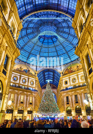 Menschen zu Fuß auf die Galleria Vittorio Emanuele II durch Weihnachtsbeleuchtung und ein glänzender Weihnachtsbaum beleuchtet. Mailand, Lombardei, Italien. Stockfoto