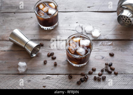 Schwarzer russischer Cocktail mit Wodka und Kaffeelikör. Hausgemachten Alkohol versoffenen Black Russian Drink mit Kaffeebohnen auf hölzernen Hintergrund mit Kopie Raum Stockfoto