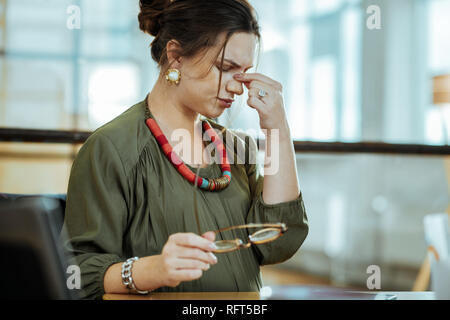 Schwangere dunkelhaarige Frau mit starken Kopfschmerzen bei der Arbeit Stockfoto