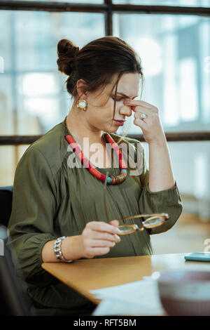 Dunkelhaarige Frau mit stilvollen Accessoires, Müdigkeit Stockfoto