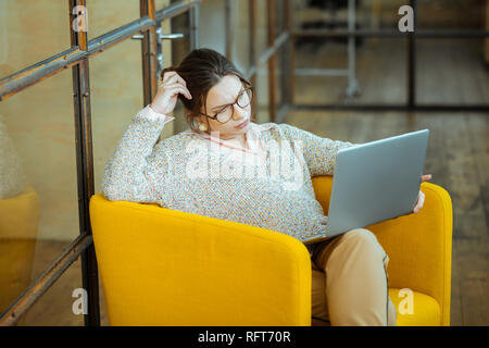 Geschäftsfrau tragen Pullover und Gläser während der Arbeit am Laptop Stockfoto