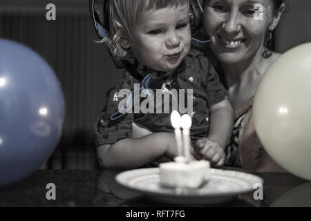 Das Porträt einer Happy Birthday Boy und seine lächelnde Mutter Abblasen des Geburtstag Kerzen. Luftballons im Vordergrund. Stockfoto