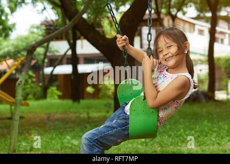 Asiatische Mädchen auf der Schaukel spielen an einem Park. Filipina Kid. Stockfoto