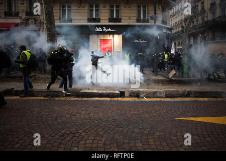 Eine gelbe Weste Demonstrant wirft zurück das Gas Kanister zur Polizei (nicht abgebildet), die während einer Demonstration gegen Längestrich Politik reißen. Gelbe weste Demonstranten versammelt und auf den Straßen von Paris ein weiteres Samstag auf, was Sie die Akte XI gegen den französischen Präsidenten Emmanuel Längestrich Politik Anruf März. Stockfoto