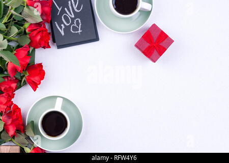 Ein Strauß roter Rosen und frischen aromatischen Tee für ein romantisches Frühstück. Worte der Liebe, die in einer Notiz und ein Geschenk mit Blumen. Valentinstag und Muttertag Stockfoto