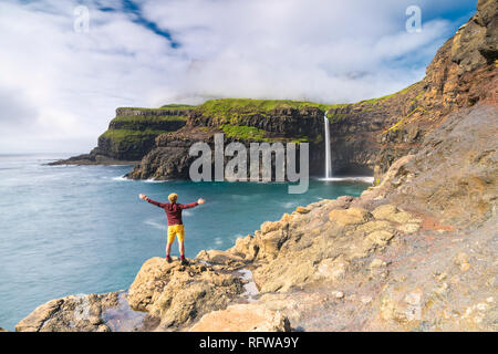 Mann auf Klippen mit offenen Armen Gasadalur Wasserfall bewundern, Vagar Island, Färöer, Dänemark, Europa Stockfoto