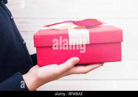 Echten Box mit weißen und roten Bogen und Farbband im Mädchen die Hände am Valentinstag isoliert auf weißem Hintergrund. Kopieren Sie Platz. Stockfoto