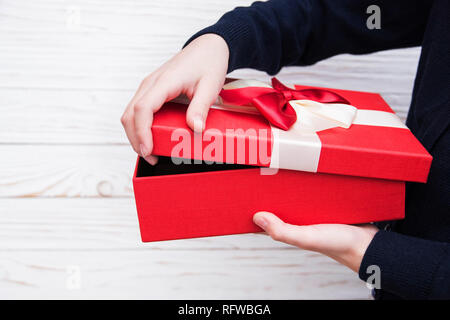 Echten Box mit weißen und roten Bogen und Farbband im Mädchen die Hände am Valentinstag isoliert auf weißem Hintergrund. Kopieren Sie Platz. Stockfoto