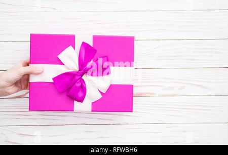 Echten Feld mit weißem und rosa Schleife und Band in der Hand am Valentinstag isoliert auf weißem Hintergrund. Platz kopieren Stockfoto