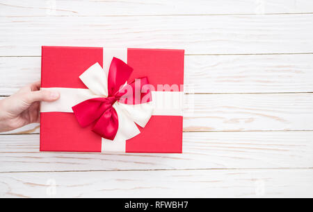 Echten Box mit weißen und roten bogen und farbband in der Hand am Valentinstag isoliert auf weißem Hintergrund. Platz kopieren Stockfoto