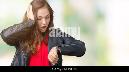 Schöne Übergrößen junge Frau trägt einen Mode Leder Jacke über isolierte Hintergrund ein Blick auf die Uhr Zeit Sorgen, Angst, sich spät Stockfoto