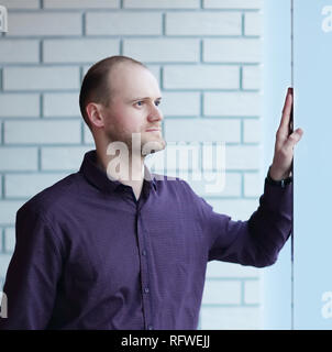 Nachdenkliche Menschen an etwas denken, der hinter der Jalousie Stockfoto