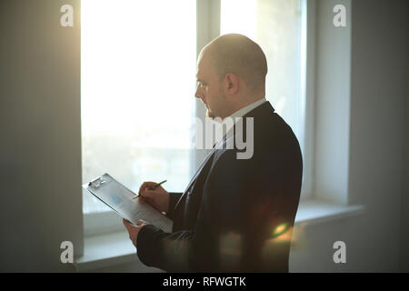 Nach Geschäftsmann Unterzeichnung Dokument in der Nähe von Büro Fenster. Stockfoto